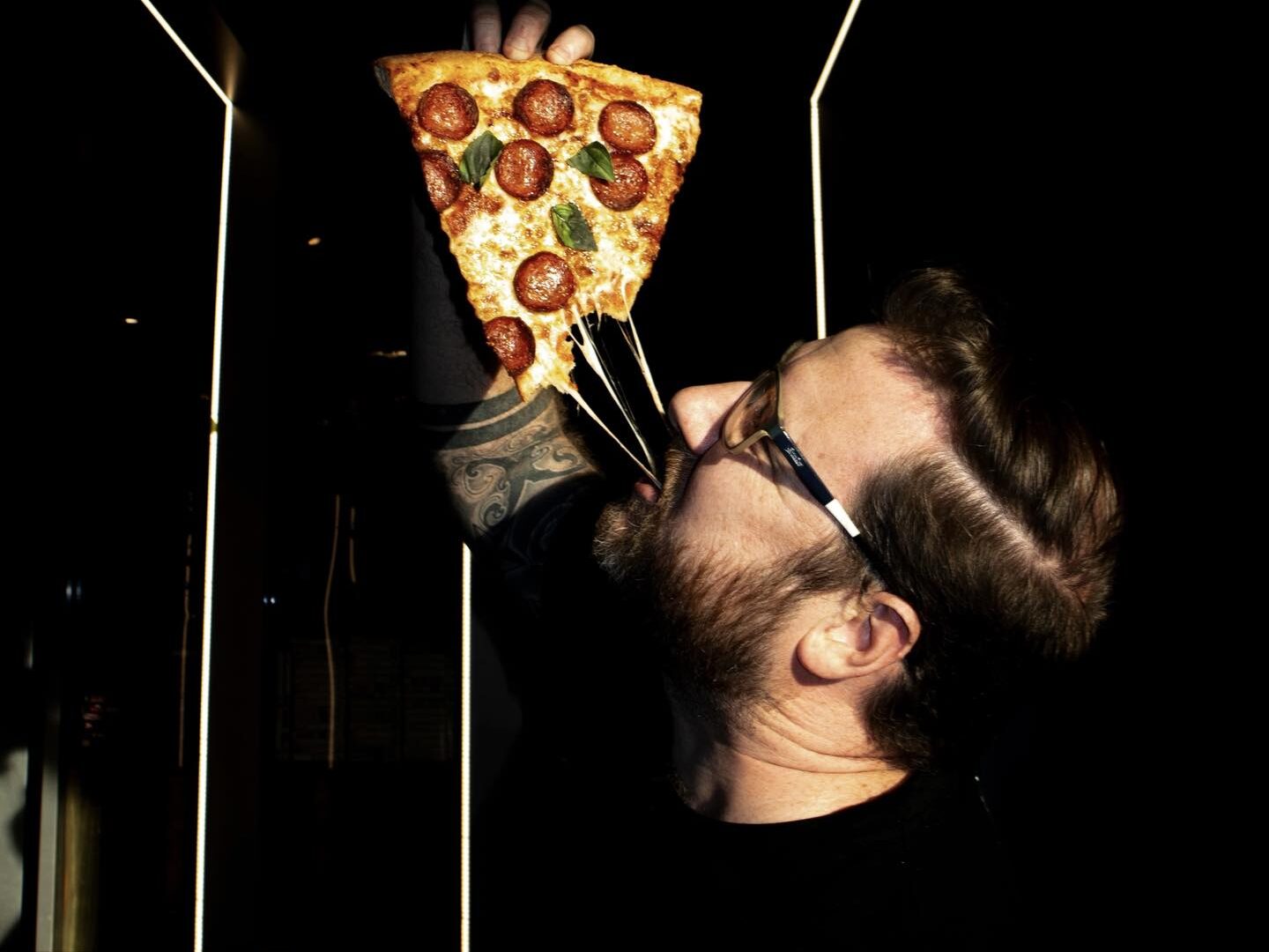 A man eating pizza while playing games at Palace Arcade, combining fun and food
