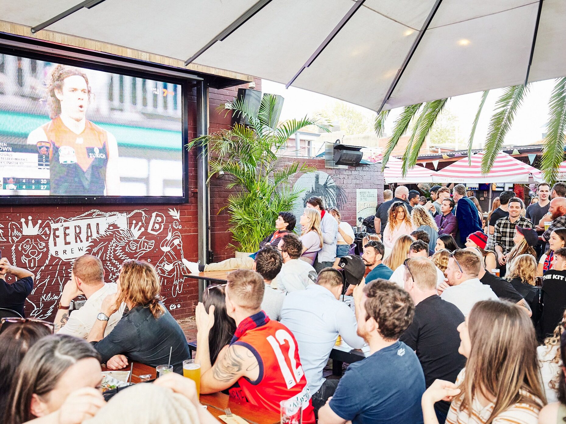 Lively footy crowd at The Broken Hill enjoying drinks watching the game in Victoria Park.