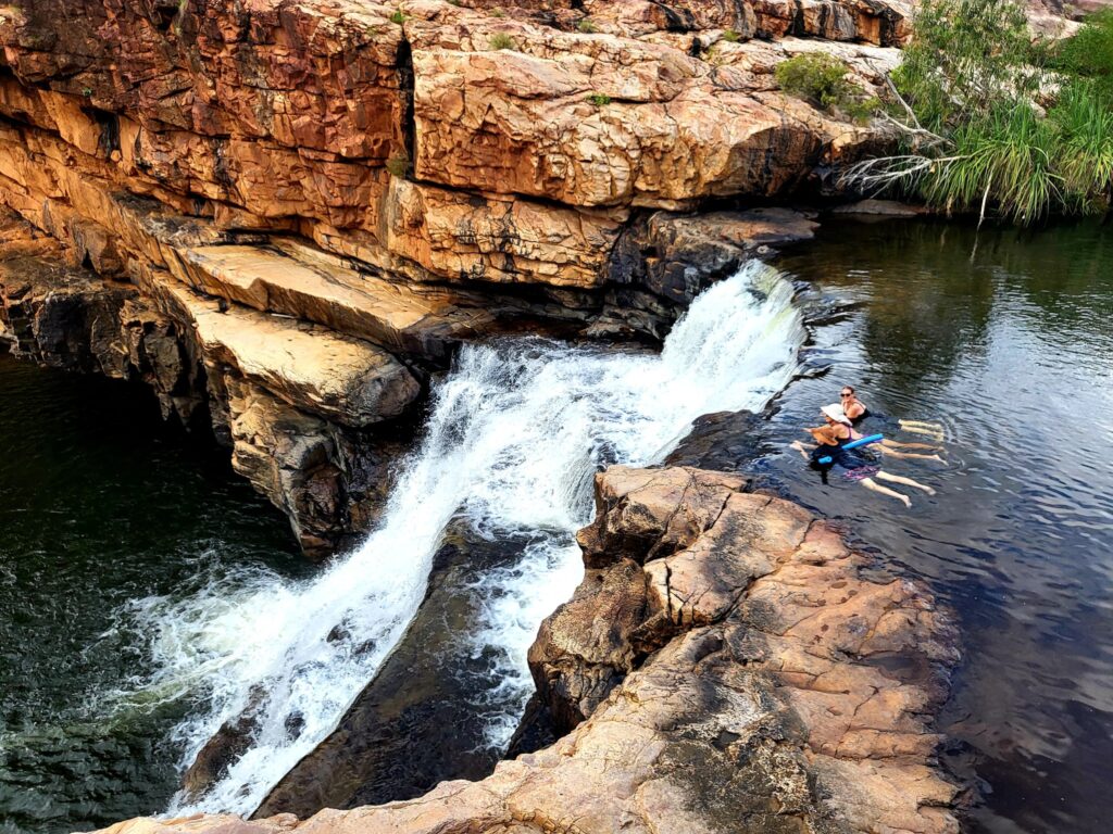 Tourists swimming at the top of a short waterfall in the Kimberley