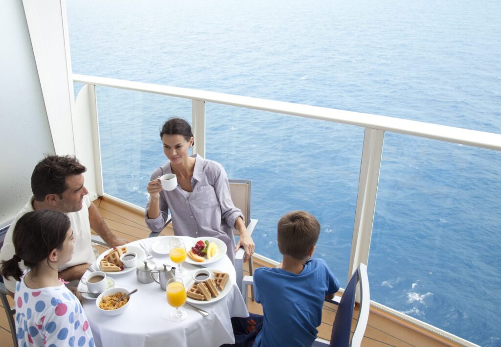 Family enjoying breakfast with a view on the balcony of a cruise ship