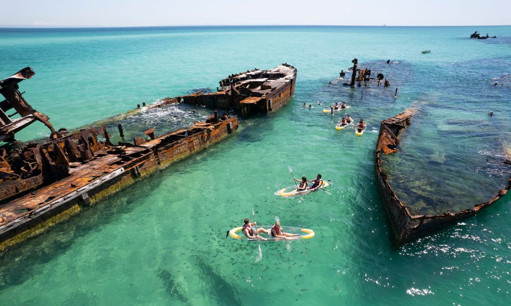 Tourists kayaking between a shipwreck in Moreton Island